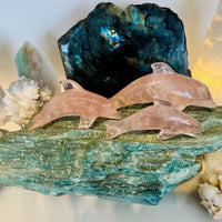 3 rose quartz dolphins on Fuchsite boulder with Labradorite and quartz on white bookshelf