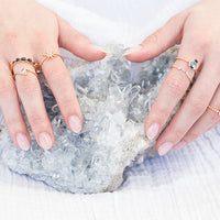 Two hands wearing rings on a white background