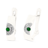 A pair of 18kt white gold emerald and diamond earrings with a green emerald centerpiece surrounded by smaller clear diamonds set within a gold band.