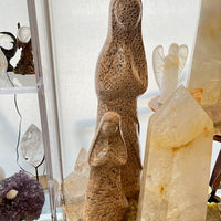 Mineral and crystal display with 2 stone sculptures of the madonna and clear crystals.