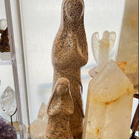 Mineral and crystal display with 2 stone sculptures of the madonna and clear crystals.