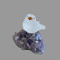 Crystal bird figurine on a amethyst crystal base with a wooden background