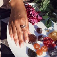 hand wearing large morganite ring on forefinger with mulitple colored stones in white plate