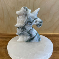Decorative stone unicorn carving on a white base against a wooden background