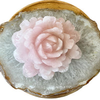 Carved large rose quartz flower sitting on a quartz slab