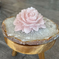 Side view of large rose quartz flower statement decor crystal on stool