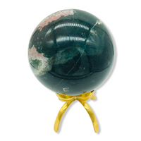 side view of the green and pink ocean jasper sphere on brass stand