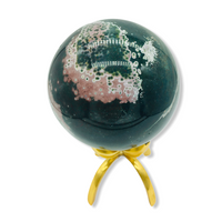 green ocean jasper orb with pink on a brass stand against white background