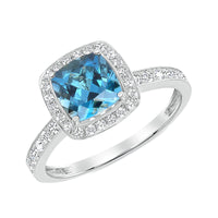White Gold ring with a cushion-cut Brilliant blue Topaz gemstone, haloed in radiant diamonds with additional pavé diamonds cascading down the band