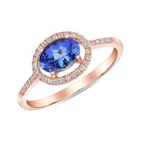 A tanzanite and diamond ring with an 18k rose gold band, featuring a central oval tanzanite surrounded by a halo of round diamonds with additional diamonds down the shank.