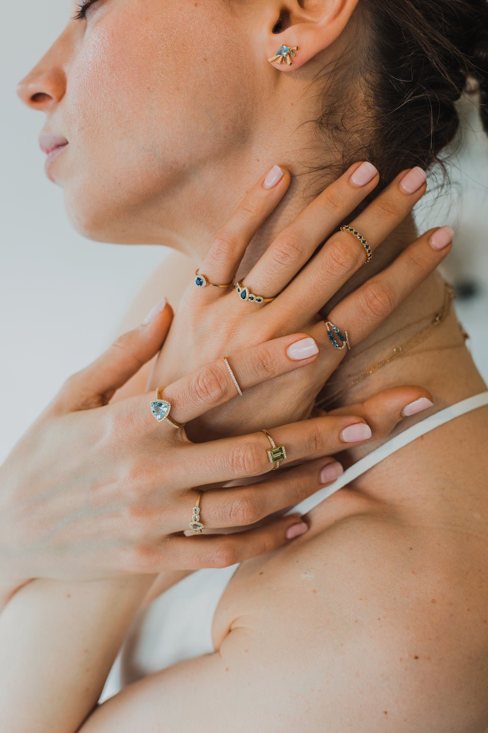 woman with multiple rings on both hands and earring with blue gemstones