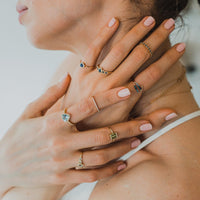 woman with multiple rings on both hands and earring with blue gemstones