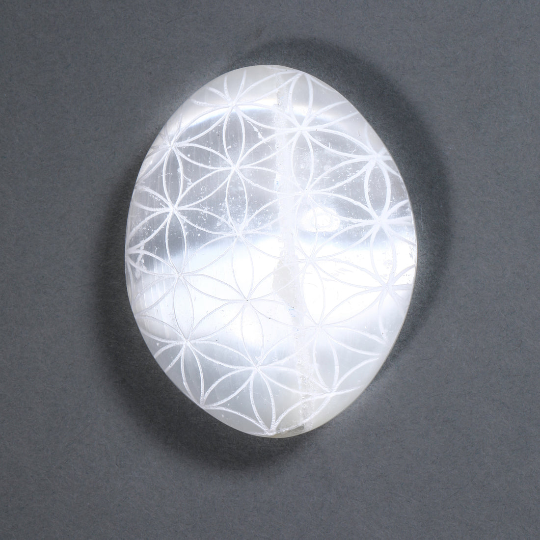 Crystal with Flower of Life pattern on a dark gray background