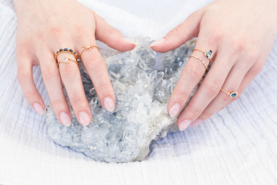 Two hands wearing rings on a white background