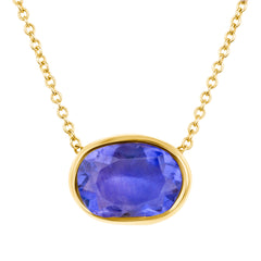 Gold necklace with a blue gemstone pendant on a white background