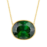 Green gemstone necklace with gold chain on a white background