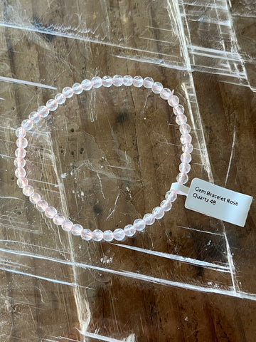 Clear beaded bracelet on a wooden surface with a label