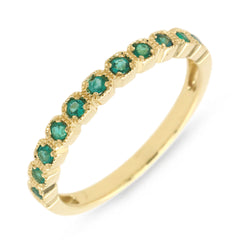 An 18k gold ring with multiple emerald stones set around its circumference.