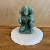 Green Aventurine statue on a white base against a wooden background