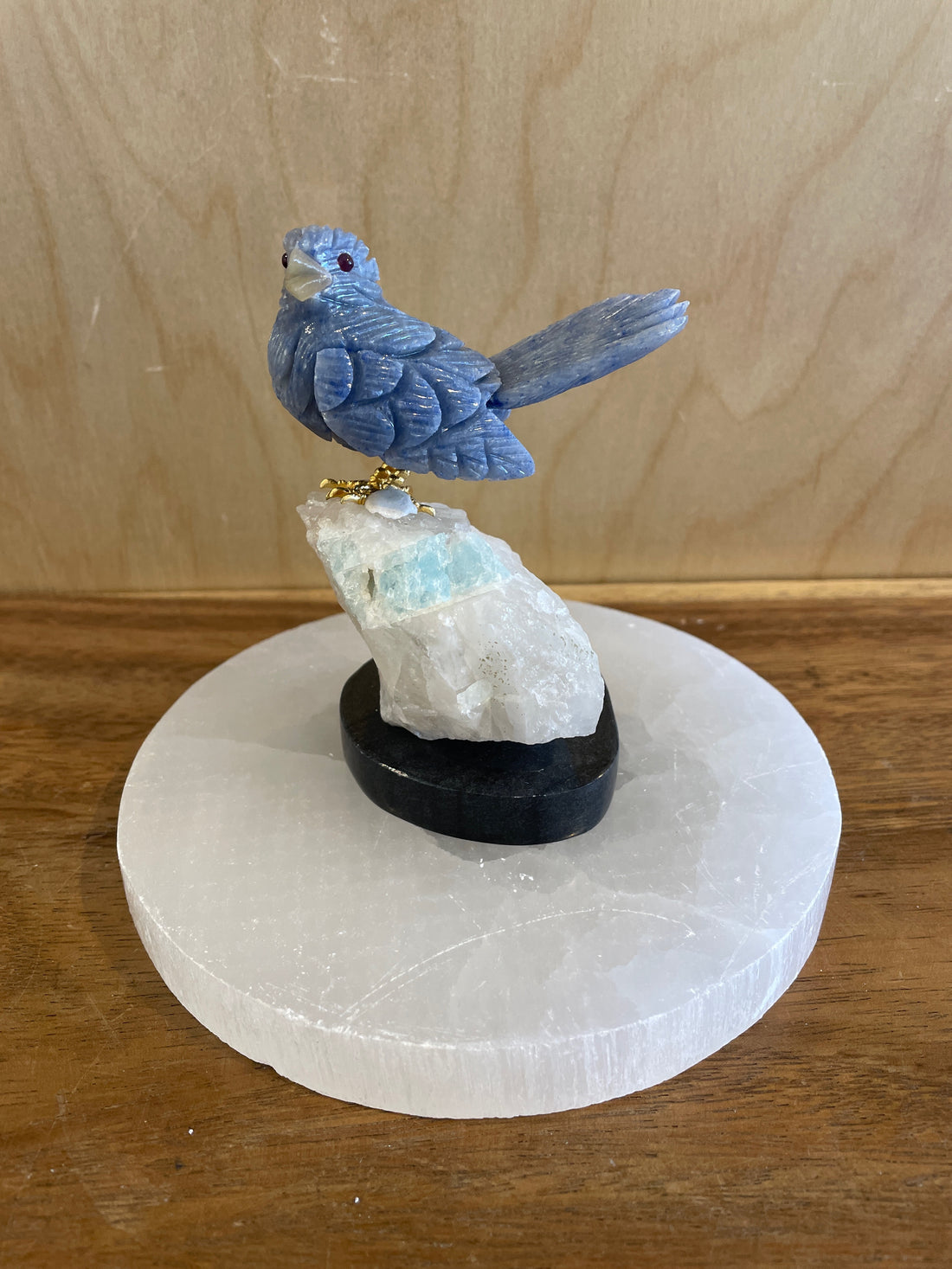 Blue bird figurine on a crystal base with a wooden background