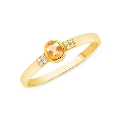 Oval cut citrine centerstone in gold ring flanked by 8 small diamonds on the band.