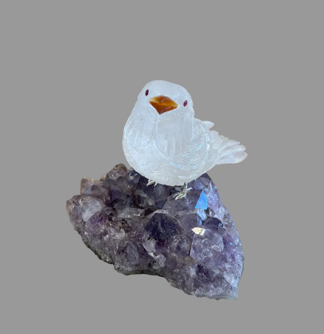 Crystal bird figurine on a amethyst crystal base with a wooden background