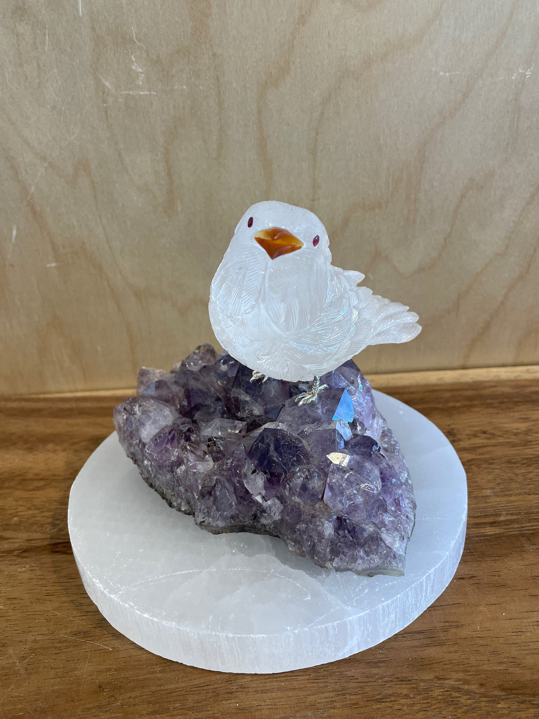 Crystal bird figurine on a amethyst crystal base with a wooden background