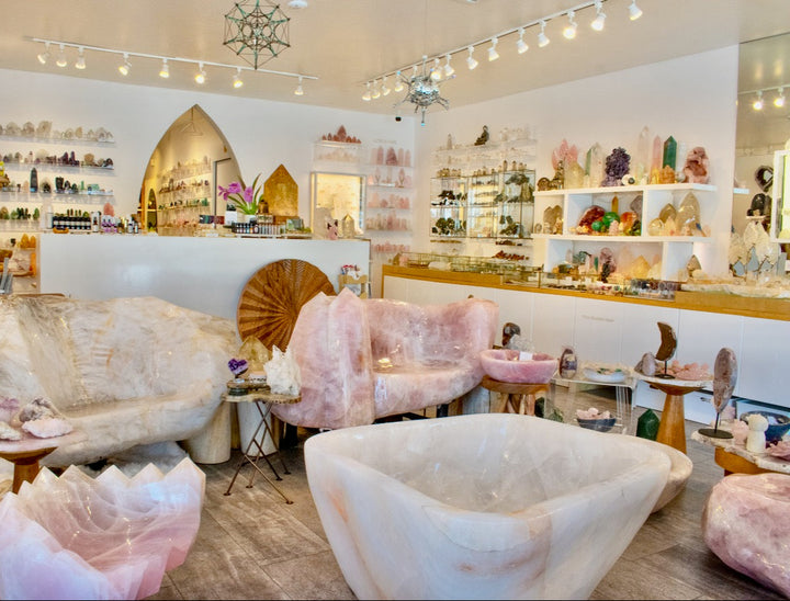 Decorative interior with pink and white furniture and shelves filled with decorative items.