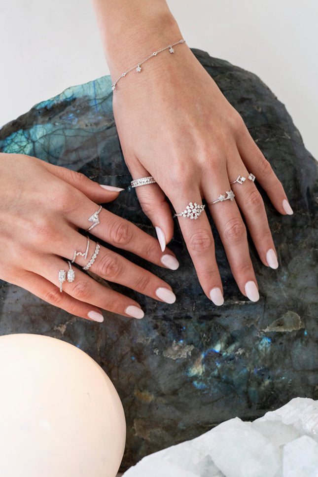 Close-up of hands wearing multiple white gold and diamond rings on a labradorite stone