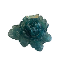 Green crystal flower on a white stone base against a wooden background