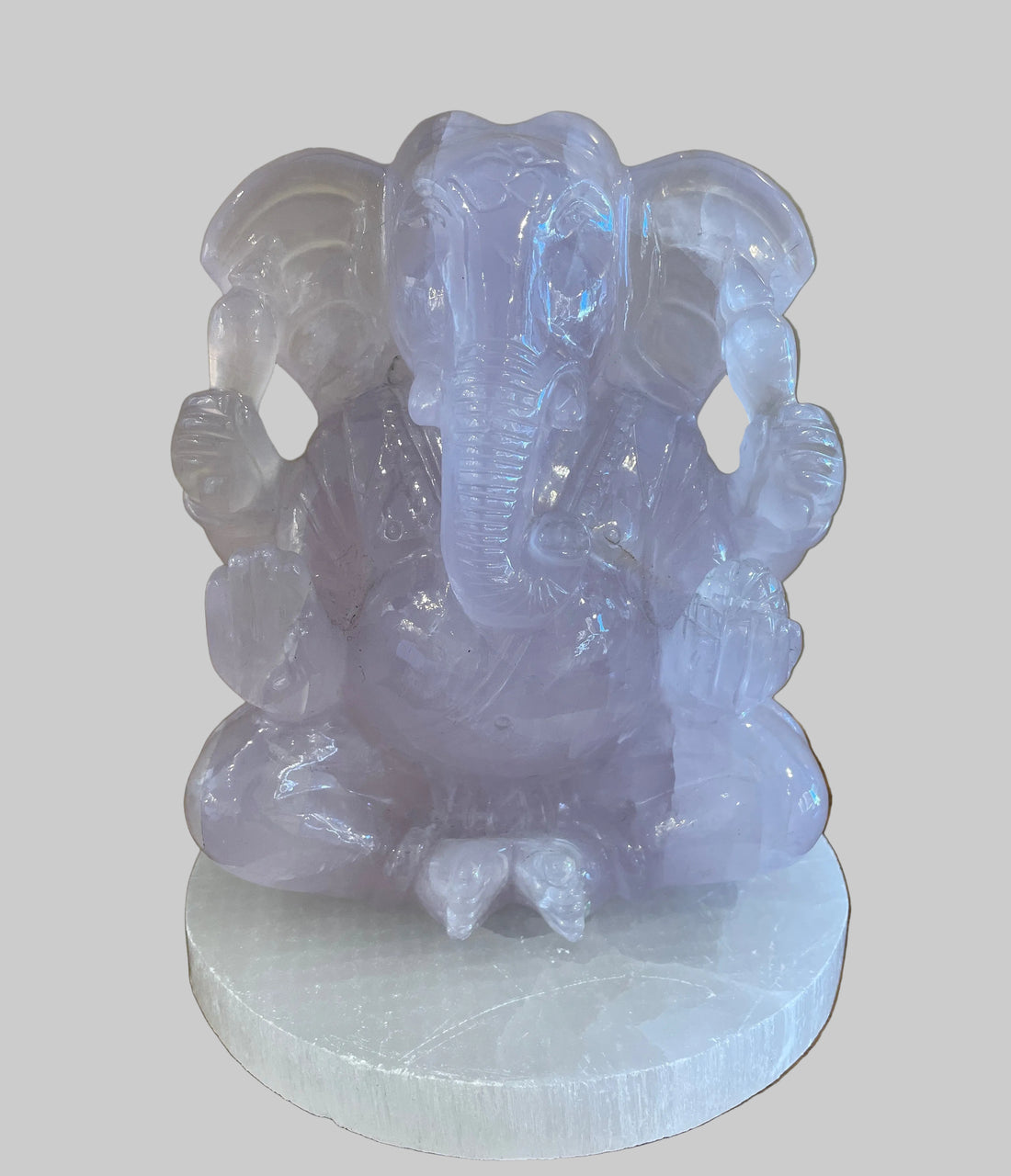 light amethyst crystal statue of a seated ganesha on a wooden surface