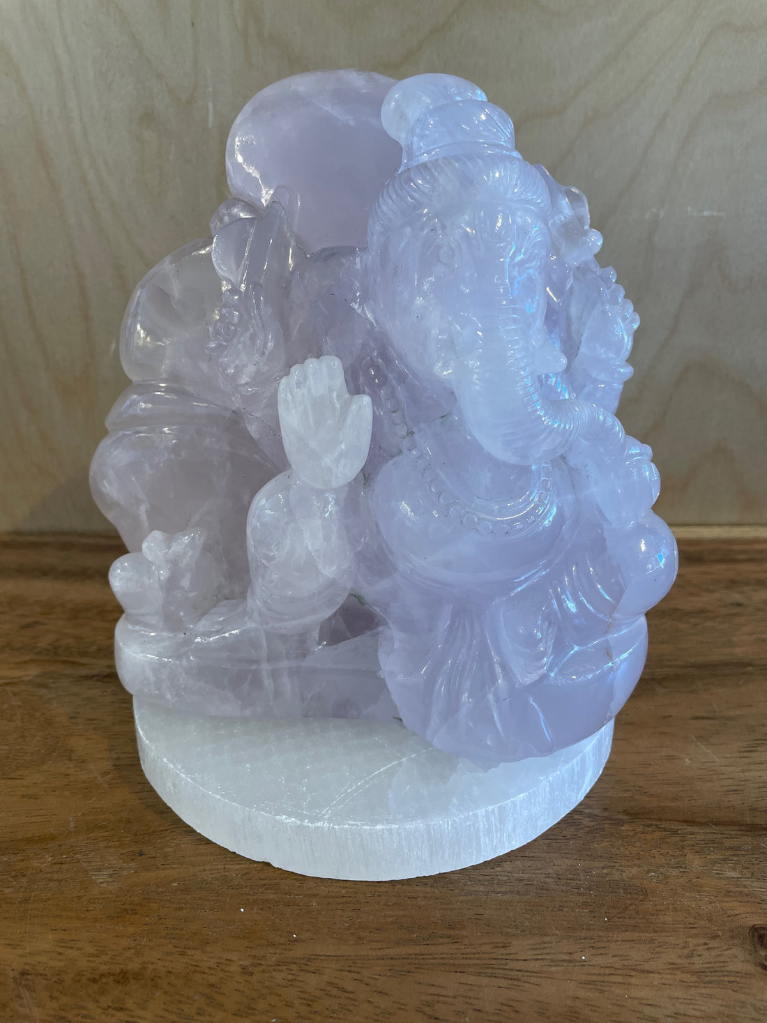 Crystal statue of a seated ganesha on a wooden surface