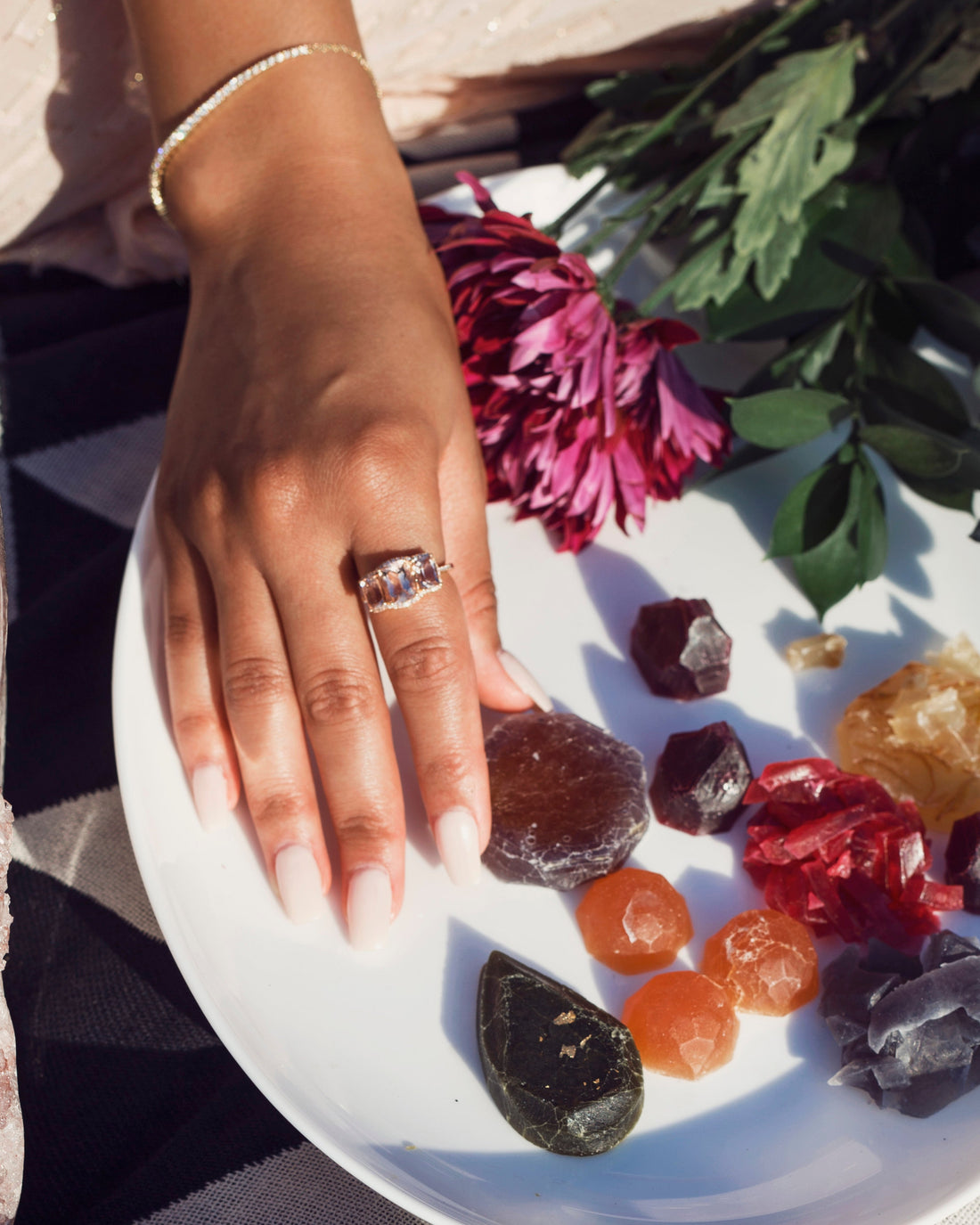 hand wearing large morganite ring on forefinger with mulitple colored stones in white plate
