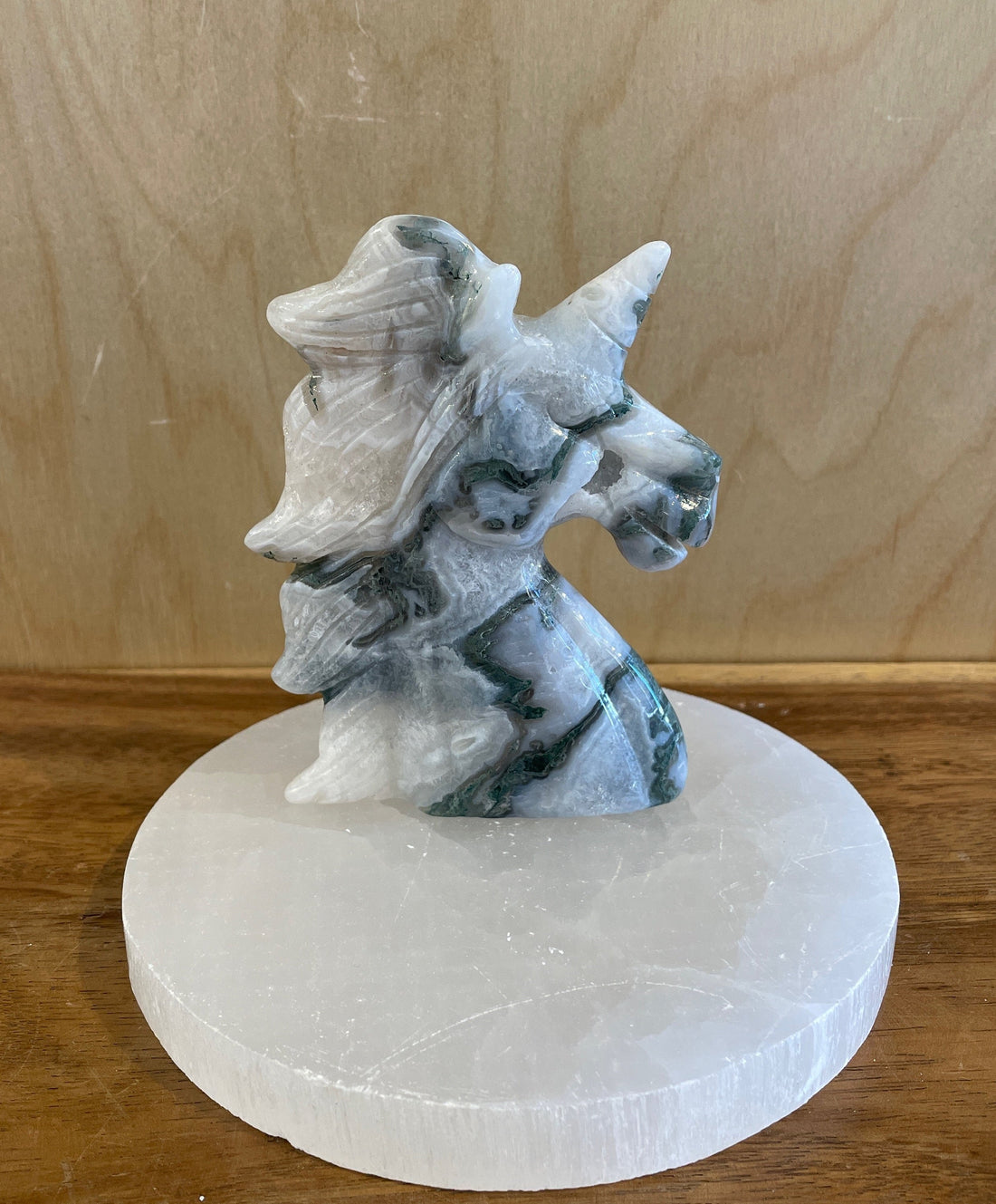 Decorative stone unicorn carving on a white base against a wooden background