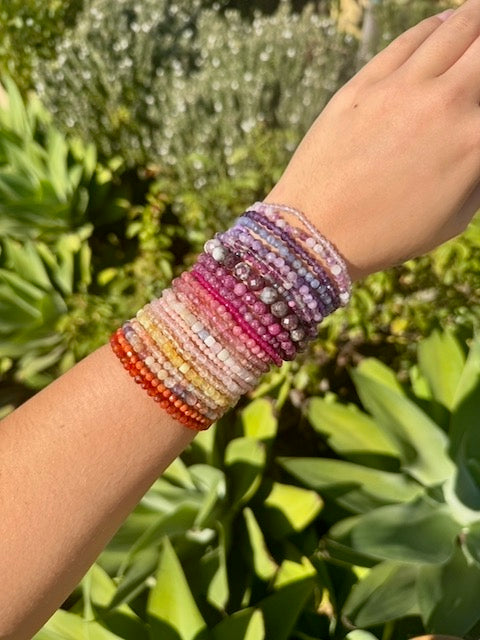 Multicolored beaded bracelet on a wrist with a green outdoor background