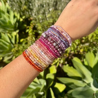 Multicolored beaded bracelet on a wrist with a green outdoor background