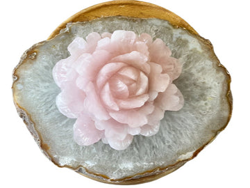 Carved large rose quartz flower sitting on a quartz slab