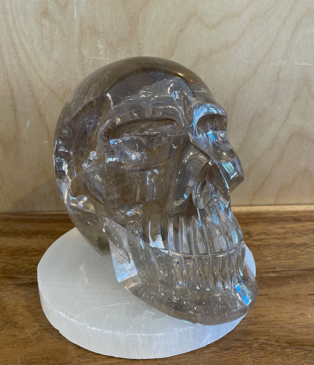 Crystal skull on a white base against a wooden background