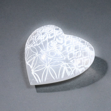 Heart-shaped selenite with etched pattern on a gray background