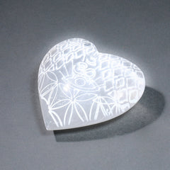 Heart-shaped selenite with etched pattern on a gray background