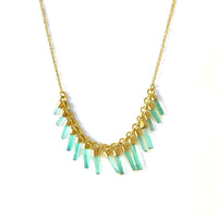 An 18k gold necklace with a series of columnar emeralds set in individual bezels, arranged in a line across the necklace.