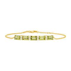 A peridot bracelet with gold chain and gold accents, featuring multiple green gemstones arranged in a line.